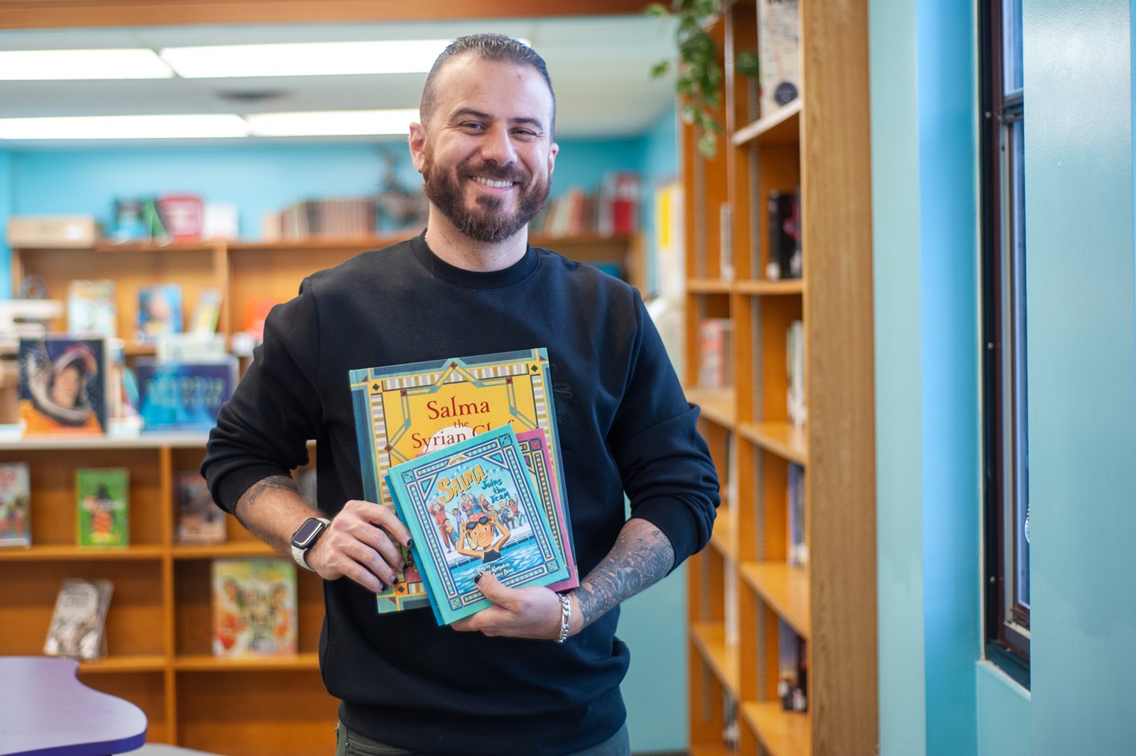 Danny smiles while holding up copies of his Salma books